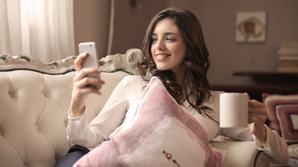 Consultation d'un smartphone, installée dans un canapé